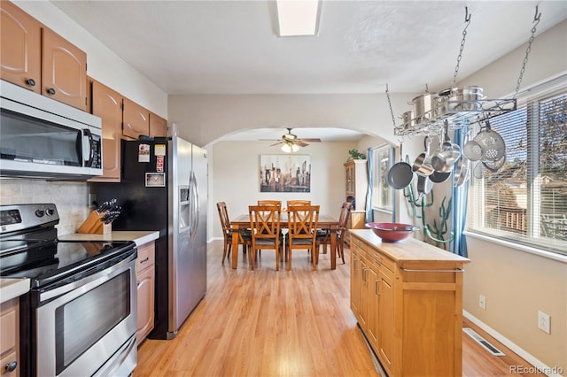 kitchen featuring stainless steel appliances, tasteful backsplash, ceiling fan, and light hardwood / wood-style floors