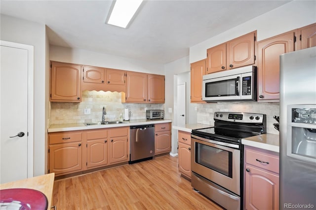 kitchen with tasteful backsplash, appliances with stainless steel finishes, light hardwood / wood-style floors, and sink