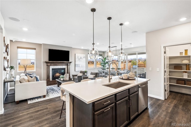 kitchen featuring sink, hanging light fixtures, stainless steel dishwasher, dark hardwood / wood-style floors, and a kitchen island with sink