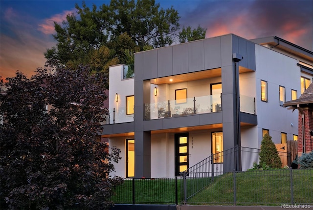 modern home featuring a fenced front yard and a lawn