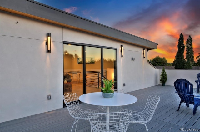 deck at dusk featuring outdoor dining area