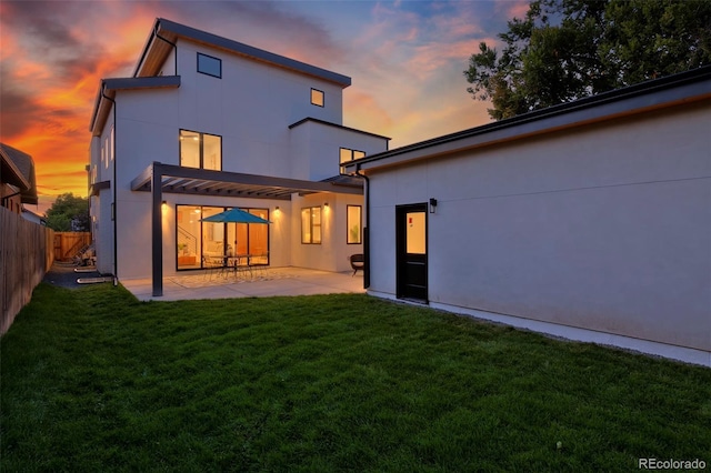 rear view of house with a patio area, a lawn, a fenced backyard, and stucco siding