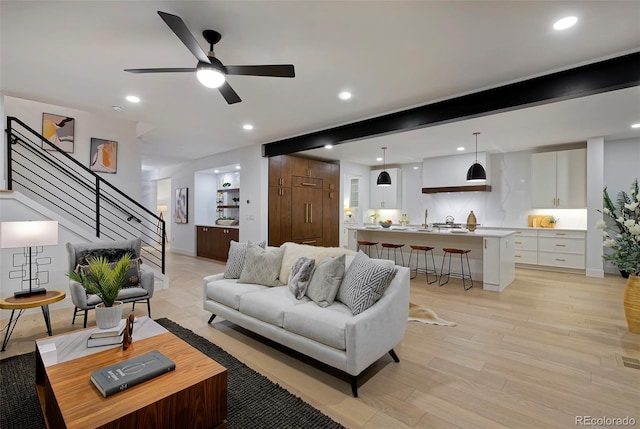 living area featuring stairway, light wood finished floors, recessed lighting, ceiling fan, and beamed ceiling