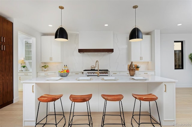 kitchen with light countertops, light wood-style flooring, recessed lighting, and a kitchen breakfast bar