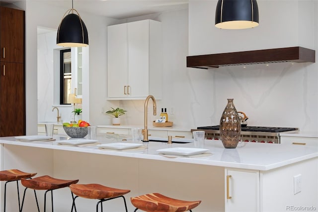 kitchen featuring premium range hood, a breakfast bar area, light countertops, decorative backsplash, and hanging light fixtures