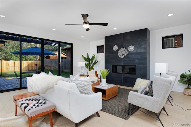 living room with recessed lighting, a fireplace, light wood-style flooring, and ceiling fan