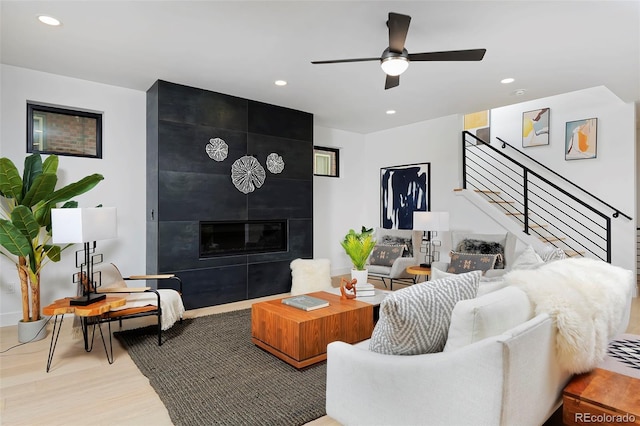 living area featuring stairway, recessed lighting, a large fireplace, and ceiling fan