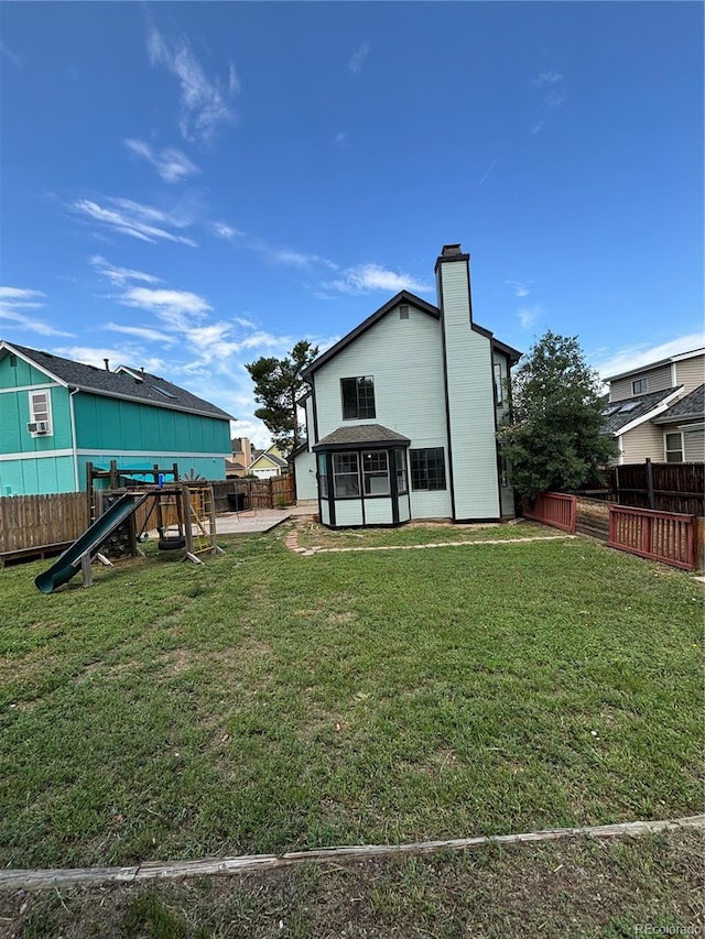 4362 Denmark Ct, Denver, CO 80239 - back of property with a chimney, a playground, a fenced backyard, and a sunroom