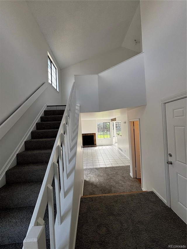 4362 Denmark Ct, Denver, CO 80239 - stairs with high vaulted ceiling, carpet floors, tile patterned flooring, and a textured ceiling