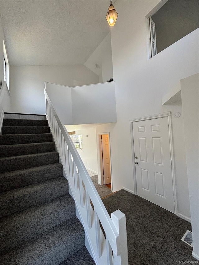 4362 Denmark Ct, Denver, CO 80239 - staircase featuring carpet floors, a textured ceiling, and high vaulted ceiling