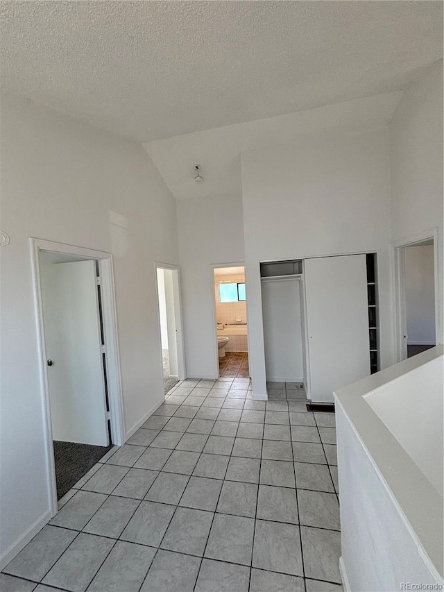 4362 Denmark Ct, Denver, CO 80239 - unfurnished bedroom featuring high vaulted ceiling, light tile patterned floors, a closet, and a textured ceiling