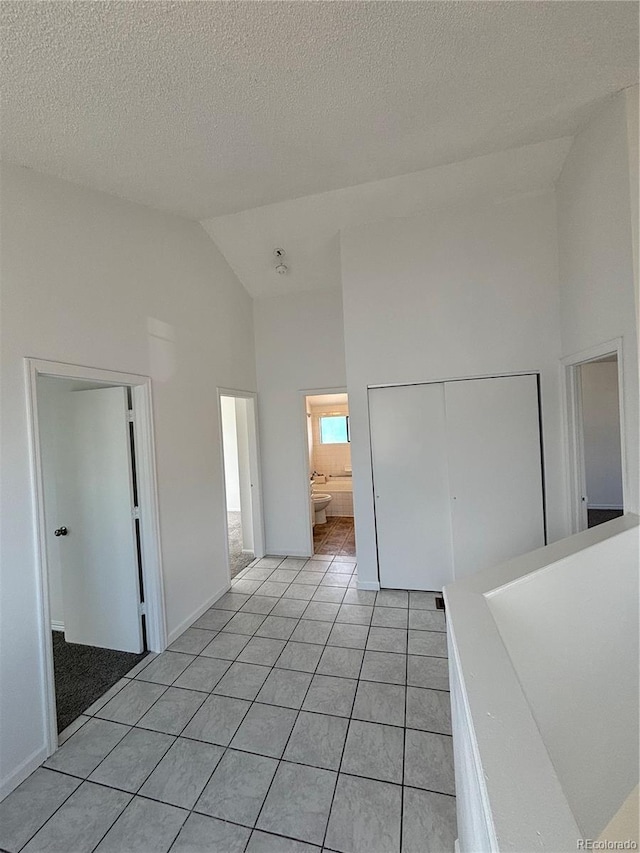 4362 Denmark Ct, Denver, CO 80239 - unfurnished bedroom featuring a closet, high vaulted ceiling, light tile patterned floors, a textured ceiling, and connected bathroom