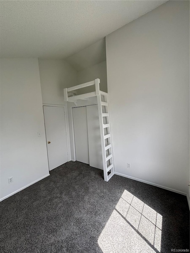 4362 Denmark Ct, Denver, CO 80239 - unfurnished bedroom with dark carpet, a textured ceiling, a closet, and lofted ceiling