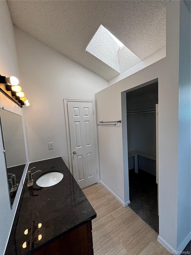 4362 Denmark Ct, Denver, CO 80239 - bathroom with vaulted ceiling, wood finished floors, a skylight, vanity, and a walk in closet