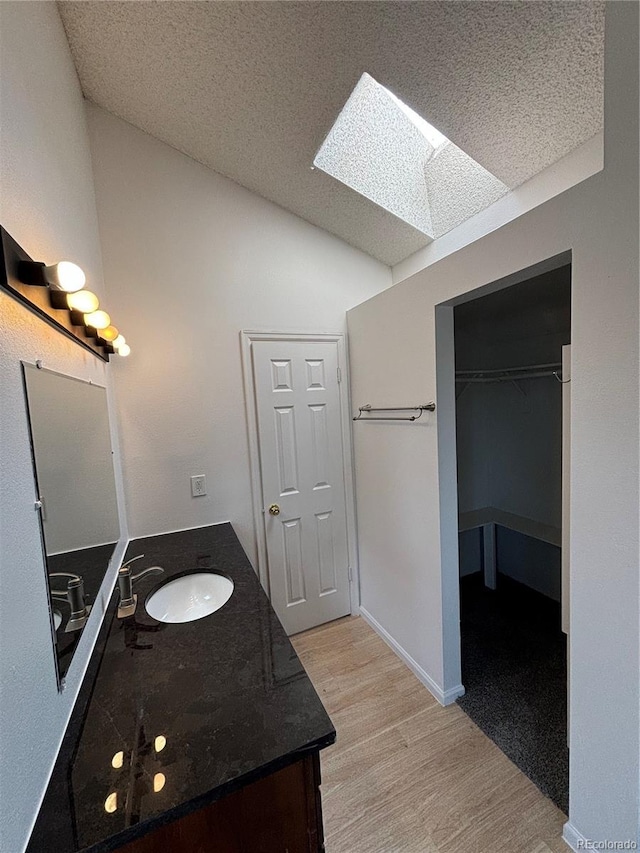 4362 Denmark Ct, Denver, CO 80239 - full bath with lofted ceiling, vanity, wood finished floors, a skylight, and a spacious closet