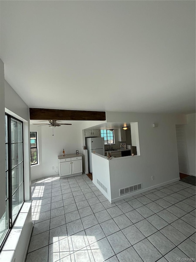 4362 Denmark Ct, Denver, CO 80239 - kitchen with light tile patterned flooring, freestanding refrigerator, a peninsula, beamed ceiling, and ceiling fan