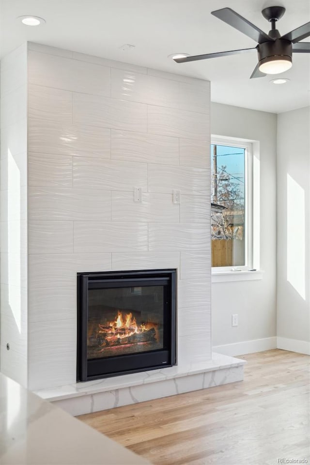 room details featuring ceiling fan, a large fireplace, and hardwood / wood-style floors