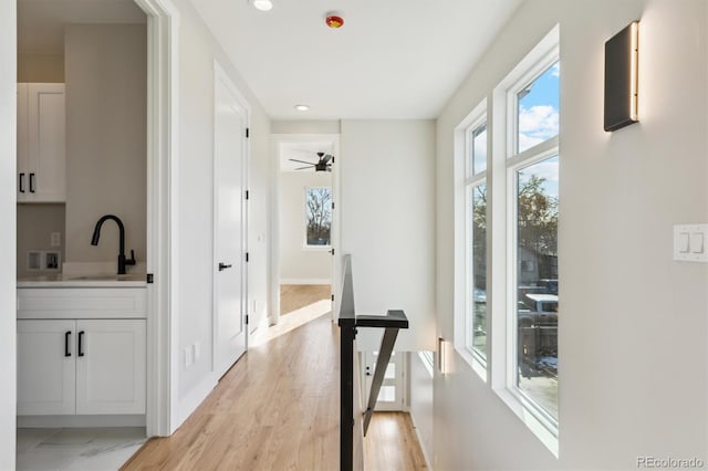 hall with light hardwood / wood-style floors and sink