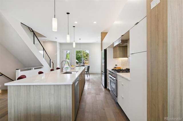 2403 S Cherokee St, Denver, CO 80223 - kitchen featuring modern cabinets, appliances with stainless steel finishes, white cabinetry, wood finished floors, and light countertops