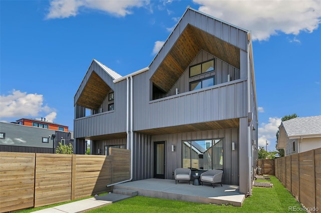2403 S Cherokee St, Denver, CO 80223 - back of property with a balcony, board and batten siding, a fenced backyard, and a patio