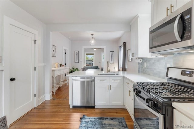 3953 Tejon St, Denver, CO 80211 - kitchen with appliances with stainless steel finishes, a sink, a peninsula, decorative backsplash, and white cabinets