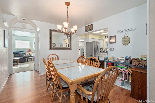 dining room with light wood-type flooring and a notable chandelier