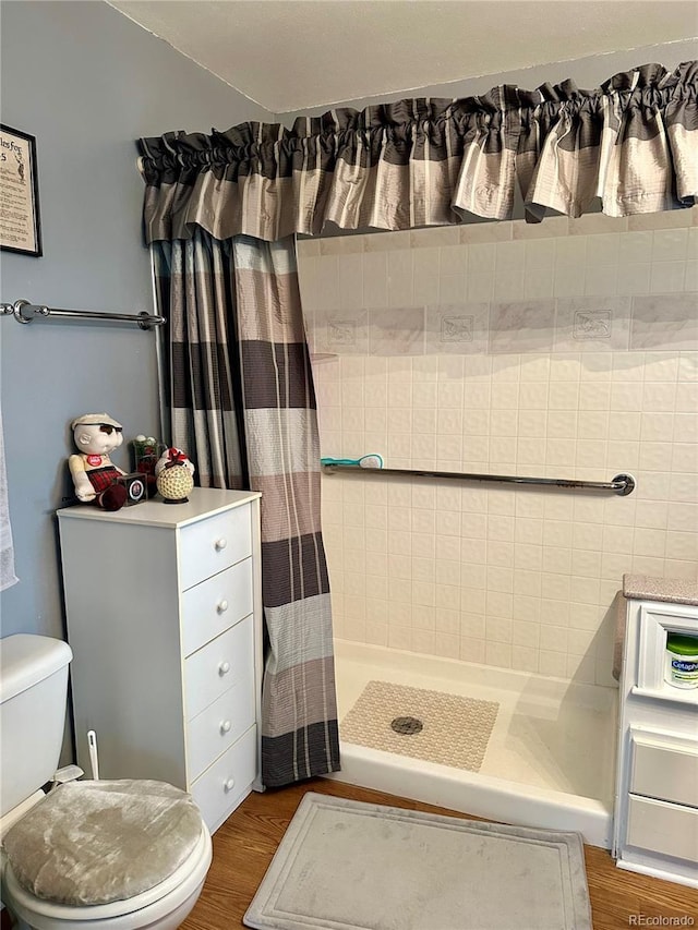 bathroom featuring a stall shower, toilet, and wood finished floors