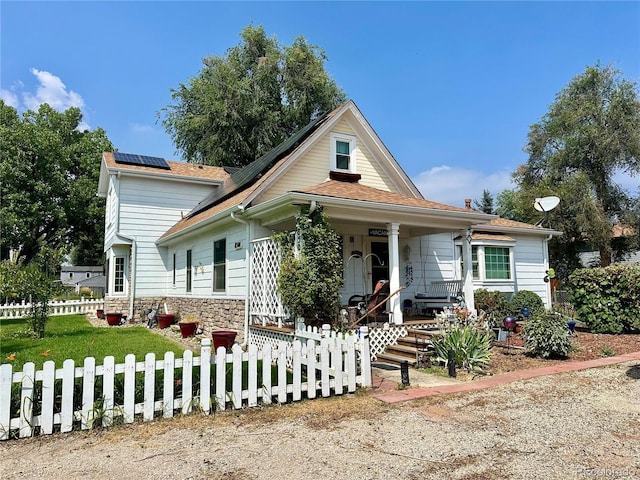 view of front of property with a porch, roof mounted solar panels, and fence private yard
