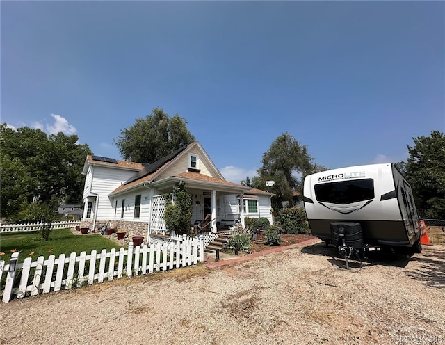 view of front of home featuring a fenced front yard, covered porch, and solar panels