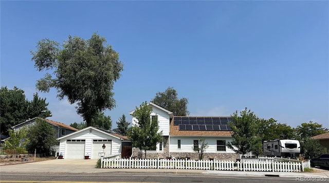 view of front of house with a garage, a fenced front yard, and solar panels