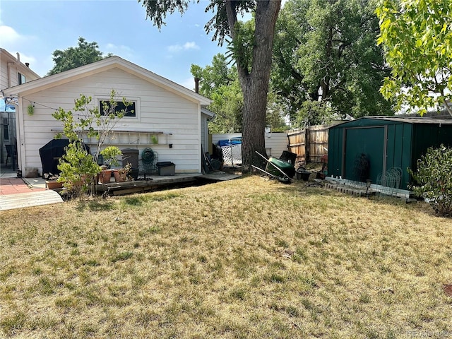 view of yard with an outbuilding, fence, and a storage shed