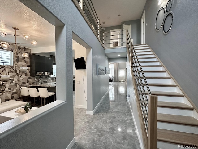 hall with stairway, marble finish floor, and baseboards