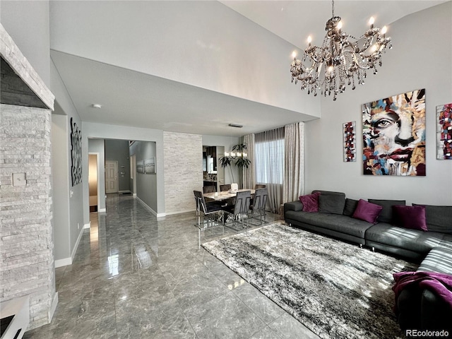 living room with a chandelier, marble finish floor, a towering ceiling, and baseboards