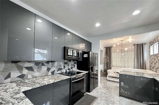 kitchen featuring stainless steel appliances, light stone countertops, a notable chandelier, and modern cabinets