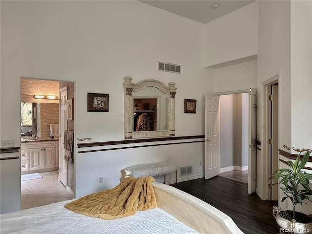 bedroom featuring a high ceiling, baseboards, visible vents, and connected bathroom