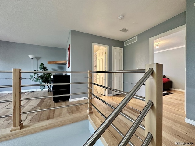 stairway featuring visible vents, baseboards, and wood finished floors