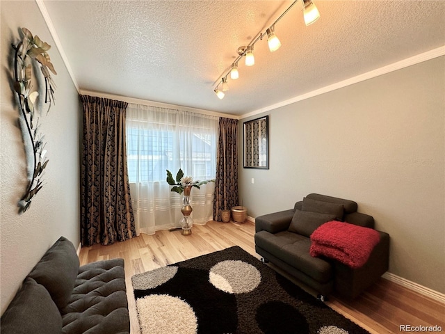living room with track lighting, a textured ceiling, baseboards, and wood finished floors