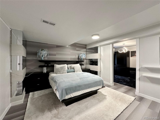 bedroom with visible vents, baseboards, and wood finished floors
