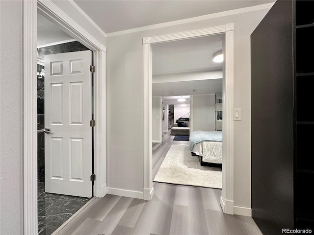 hallway with ornamental molding, baseboards, and wood finished floors