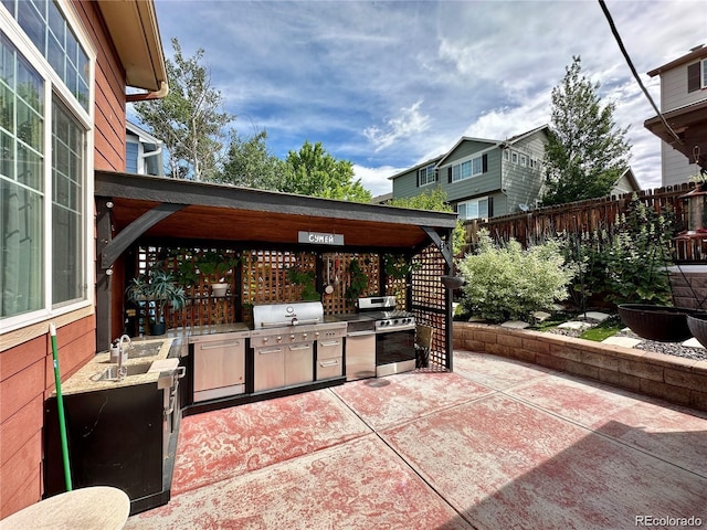 view of patio with a grill, an outdoor kitchen, a sink, and fence