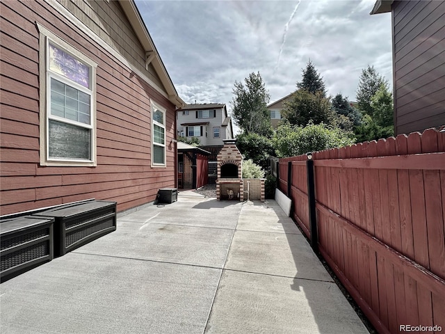view of home's exterior with a patio, fence, and an outdoor brick fireplace