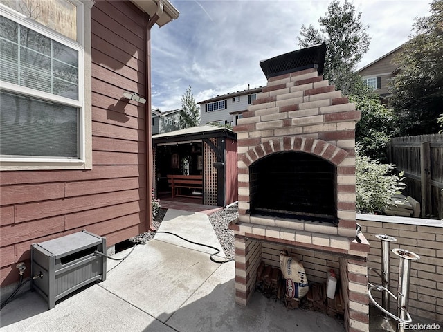 view of patio with fence and exterior fireplace