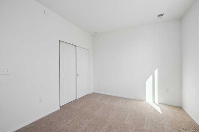 unfurnished bedroom with a closet and light carpet