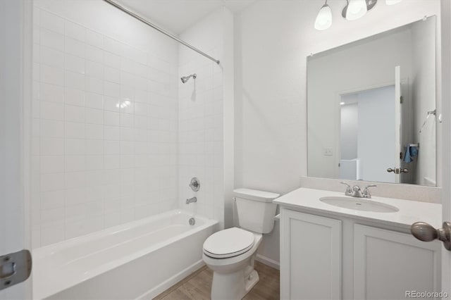 full bathroom featuring wood-type flooring, toilet, tiled shower / bath combo, and vanity