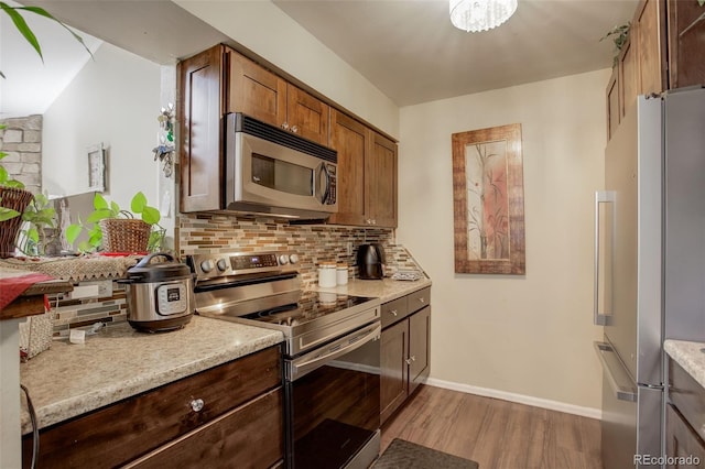 10150 E Virginia Ave Unit 18-302, Denver, CO 80247 - kitchen featuring appliances with stainless steel finishes, wood finished floors, tasteful backsplash, light countertops, and baseboards