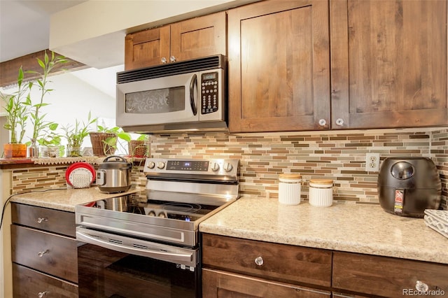 10150 E Virginia Ave Unit 18-302, Denver, CO 80247 - kitchen with appliances with stainless steel finishes, tasteful backsplash, and light stone counters