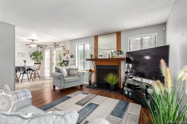 4520 E 112th Pl, Thornton, CO 80233 - living area with a textured ceiling, a fireplace with raised hearth, wood finished floors, and a ceiling fan