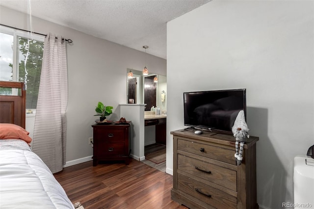 4520 E 112th Pl, Thornton, CO 80233 - bedroom featuring dark wood-style floors, a textured ceiling, baseboards, and connected bathroom