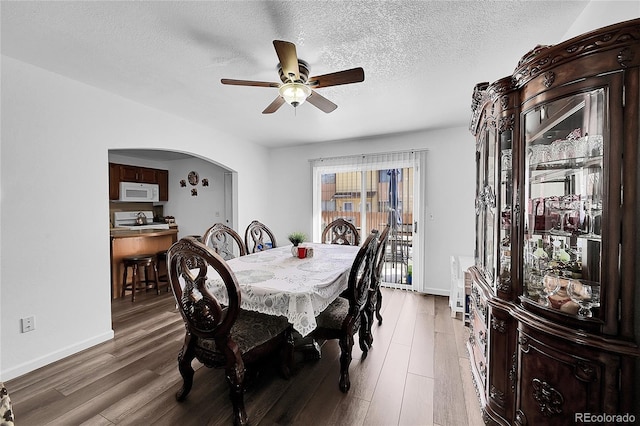 dining area featuring a textured ceiling, wood-type flooring, and ceiling fan