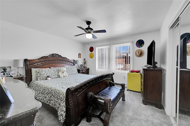 carpeted bedroom featuring ceiling fan and a textured ceiling